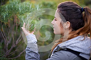 Hiking, woman and touch plants in nature on holiday, vacation or travel on adventure in winter. Trekking, bush and young