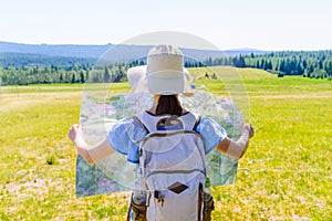 Hiking woman traveler with backpack checks map