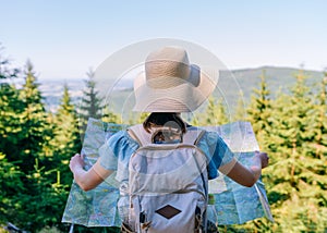 Hiking woman traveler at the crossroads with backpack checks map