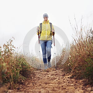 Hiking, woman and walking with trekking pole in a bush path or forest trail for exercise, workout or fitness on winter