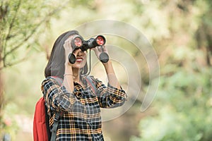 Hiking women use binoculars to travel and have a happy smile. tourist looking through binoculars considers wild birds in the