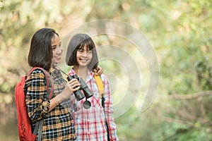 Hiking women use binoculars to travel and have a happy smile. tourist looking through binoculars considers wild birds in the