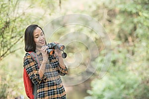 Hiking women use binoculars to travel and have a happy smile. tourist looking through binoculars considers wild birds in the