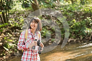 Hiking women use binoculars to travel and have a happy smile. tourist looking through binoculars considers wild birds in the