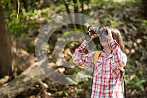 Hiking women use binoculars to travel and have a happy smile. tourist looking through binoculars considers wild birds in the