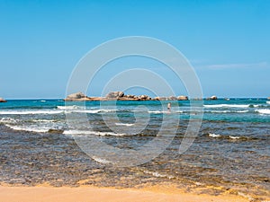 Hikkaduwa, Sri Lanka - March 8, 2022: People swim in the azure water of the Indian Ocean near the coral reef of Hikkaduwa beach.