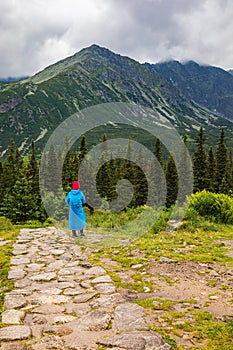 Hikker in a plastic raincoat walking in Tatra mountains, Poland in bad weather - portrait orientation photo