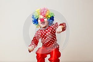 Hilarious five-year-old boy dances in clown costume and wig on white background