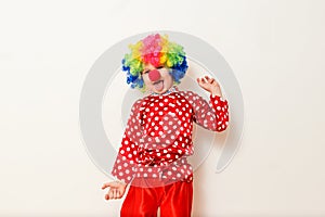 Hilarious five-year-old boy dances in clown costume and wig on white background