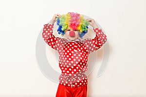 Hilarious five-year-old boy dances in clown costume and wig on white background