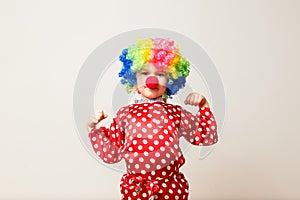 Hilarious five-year-old boy dances in clown costume and wig on white background