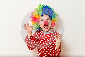 Hilarious five-year-old boy dances in clown costume and wig on white background