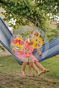Hilarious kids have fun in the courtyard showing paper emoticons