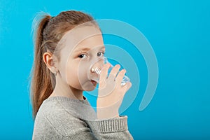 Ð¡hild drinks clear water, portrait on blue background
