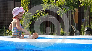 hild girl bathes in a pool under the spray of water.