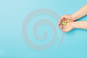 Ð¡hild hands holding green dove bird on blue background, international day of peace or world peace day concept