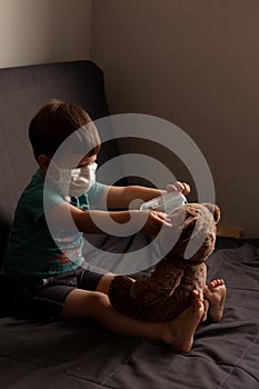 Ð¡hild and his teddy bear both in protective medical masks