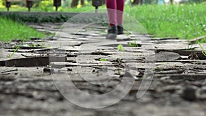 Ð¡hild legs walking away on the wooden pathway. Girl in black shoes walks in park.