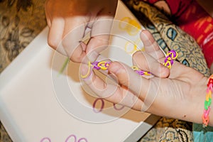 Ð¡hild making a rubber loom bracelet with a hook.Children hands