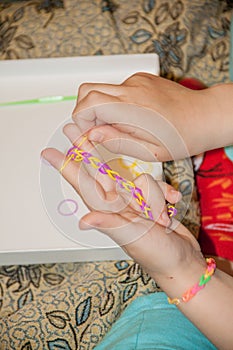 Ð¡hild making a rubber loom bracelet with a hook.Children hands