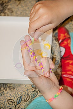 Ð¡hild making a rubber loom bracelet with a hook.Children hands