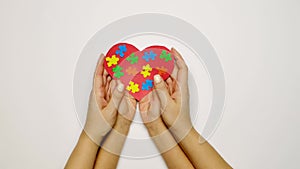 Ð¡hild, mother and father hold a heart with colorful puzzle pieces in their palms - a symbol of autism.