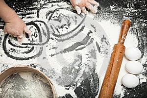 Ð¡hild`s hand is playing with flour, ingredients for baking