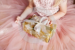 Ð¡hild`s  hands holding gold gift box. Little girl with christmas gift.  Christmas, new year, birthday concept. Festive backgroun