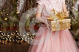 Ð¡hild`s  hands holding gold gift box. Little girl with christmas gift.  Christmas, new year, birthday concept. Festive backgroun