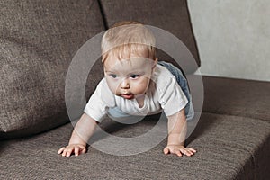 Ñhildhood babyhood and people concept happy smiling little baby boy or girl crawling on sofa
