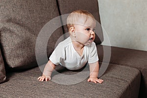 Hildhood babyhood and people concept happy smiling little baby boy or girl crawling on sofa