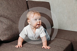 Hildhood babyhood and people concept happy smiling little baby boy or girl crawling on sofa