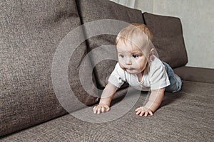 Hildhood babyhood and people concept happy smiling little baby boy or girl crawling on sofa