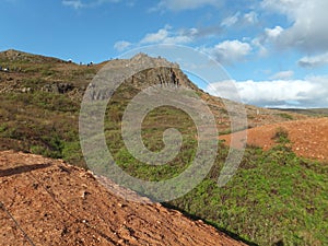 Hill in the Haukadalur Valley geothermal area; red soil and blue sky