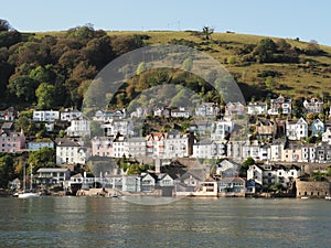 a hill in Kingswear , Devon seen across the River Dart in sunshine showing neat and colourful houses