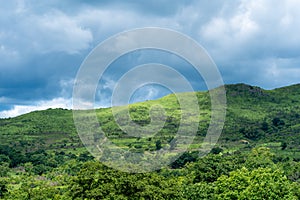 Hill landscape in the sunlight against the sky with thunder clouds