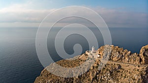 The Cabo de Tinoso lighthouse high on the mountain in the sunlight. photo