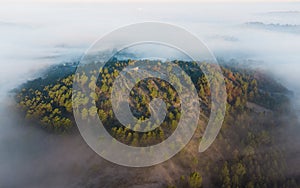 Hill overlooking the clouds. Fog surrounding a hill and submerging the surrounding hills