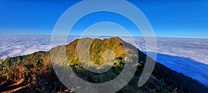 Hill surrounded by clouds and blue sky