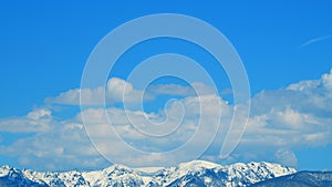 Hills Covered With Forests And Mountain Peaks Covered With Snow. Beautiful View Of The Snow Capped Mountains. Timelapse. photo