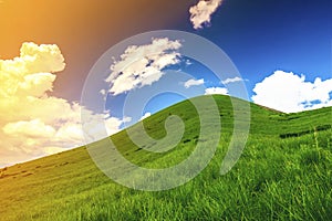 Hills with green grass and blue sky with white puffy clouds