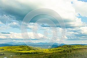 Hills with green grass and blue sky with white puffy clouds