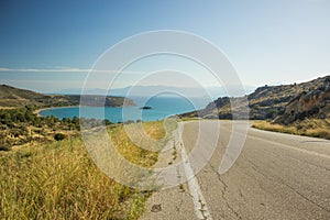 Hills highland scenic landscape from above going down with asphalt outskirts country side car road to sea bay shoreline