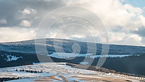 Hills with meadows and forest covered by snow