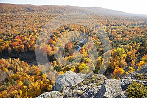 Hills and valley in Michigan with trees in brilliant fall color above a small river