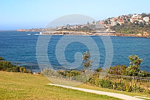 Hillside town on waterfront. Picturesque and amazing landscape with grass, shrubs and metal fences on by sea in Sydney, Australia