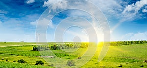 Hilly green field , sun rise and windmill on blue sky background. Wide photo