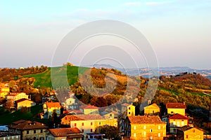 Hilly landscape with houses illuminated by beams of the setting sun in Monte Vidon Corrado