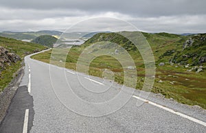 Hilly lanscape with tarmac road and grassy bogs, Norway