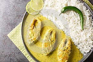 Hilsa fish in Mustard Sauce or shorshe Ilish served with white rice closeup on the plate. Horizontal top view